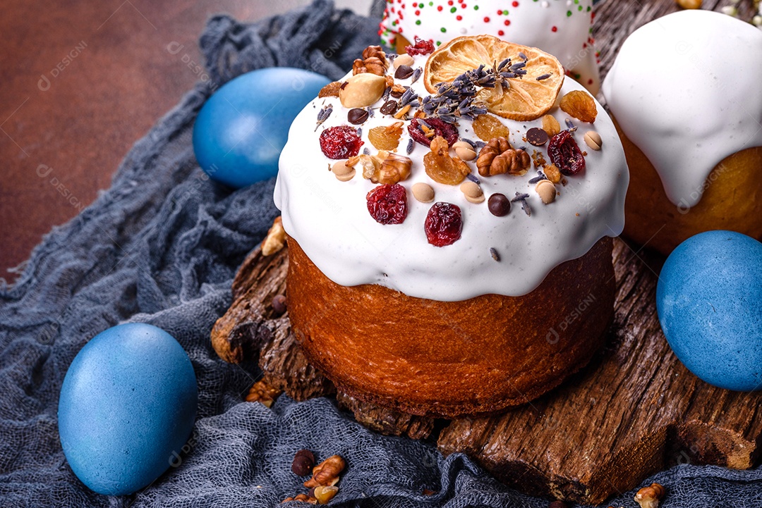 Bolos festivos com esmalte branco, nozes e passas com ovos de Páscoa na mesa festiva. Preparativos para a Páscoa