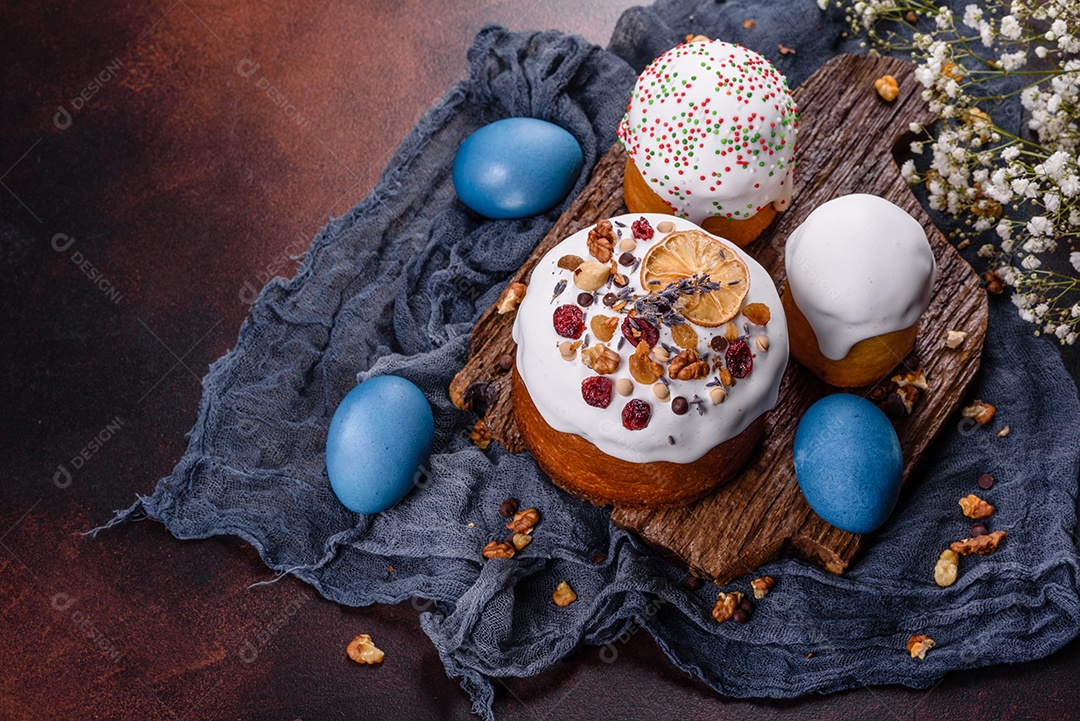 Bolos festivos com esmalte branco, nozes e passas com ovos de Páscoa na mesa festiva. Preparativos para a Páscoa