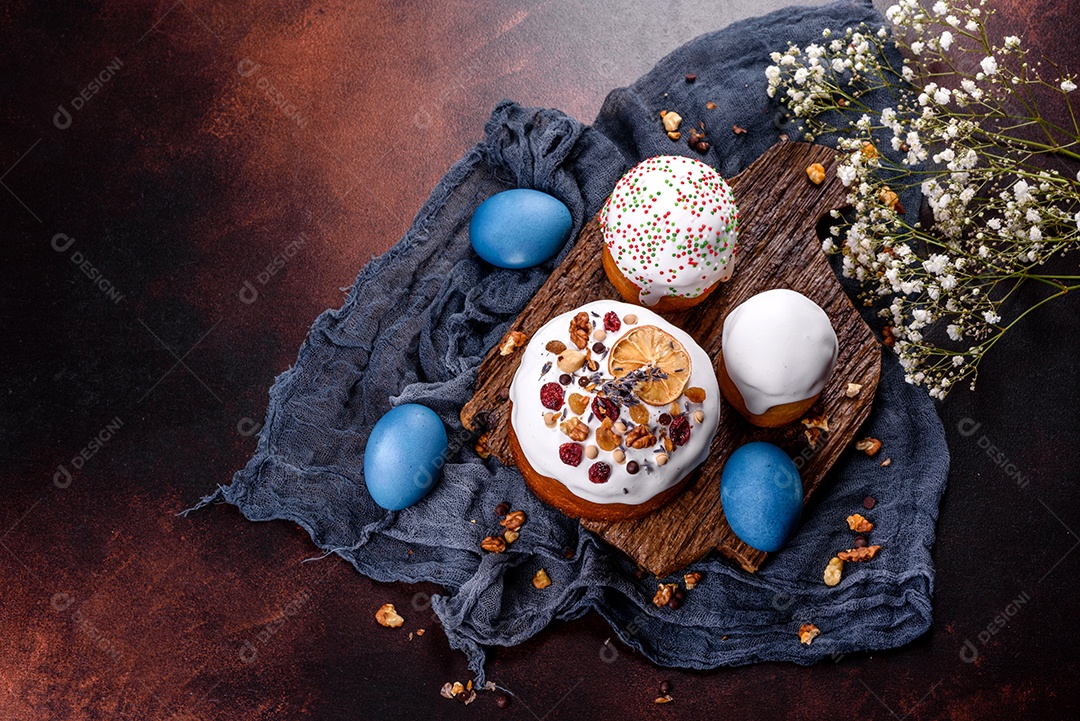 Bolos festivos com esmalte branco, nozes e passas com ovos de Páscoa na mesa festiva. Preparativos para a Páscoa