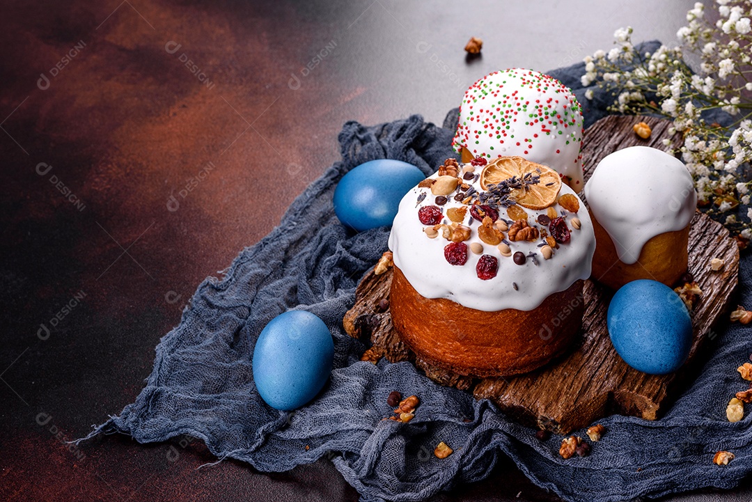 Bolos festivos com esmalte branco, nozes e passas com ovos de Páscoa na mesa festiva. Preparativos para a Páscoa
