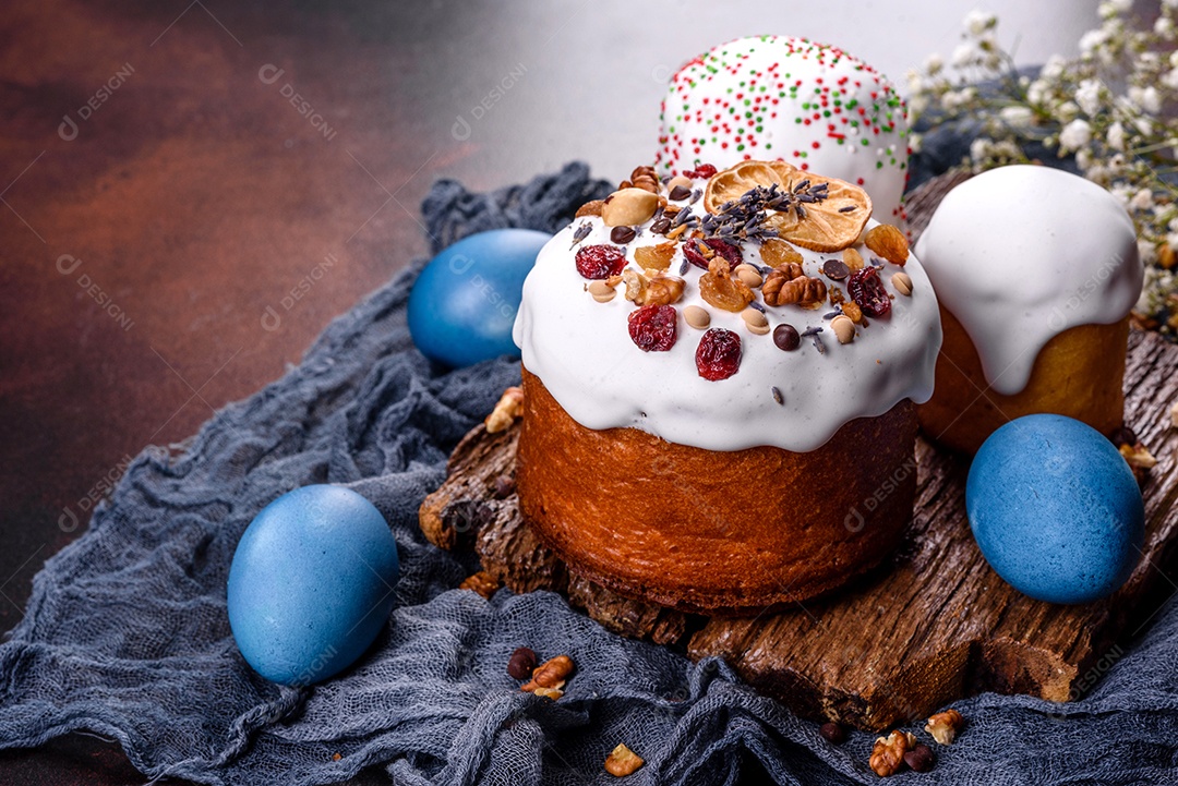Bolos festivos com esmalte branco, nozes e passas com ovos de Páscoa na mesa festiva. Preparativos para a Páscoa