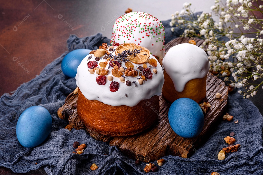 Bolos festivos com esmalte branco, nozes e passas com ovos de Páscoa na mesa festiva. Preparativos para a Páscoa