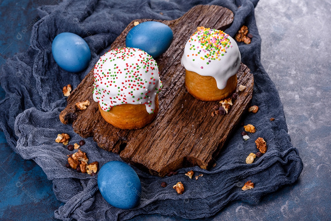 Bolos festivos com esmalte branco, nozes e passas com ovos de Páscoa na mesa festiva. Preparativos para a Páscoa