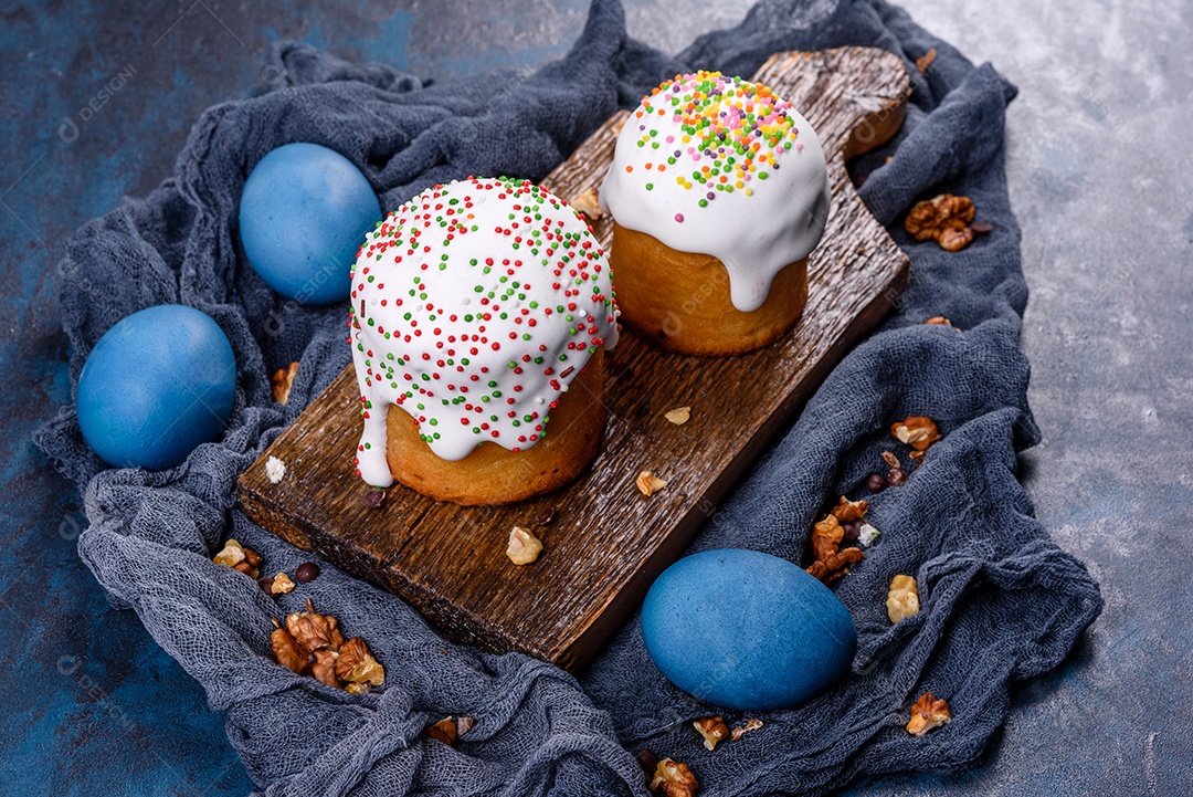 Bolos festivos com esmalte branco, nozes e passas com ovos de Páscoa na mesa festiva. Preparativos para a Páscoa