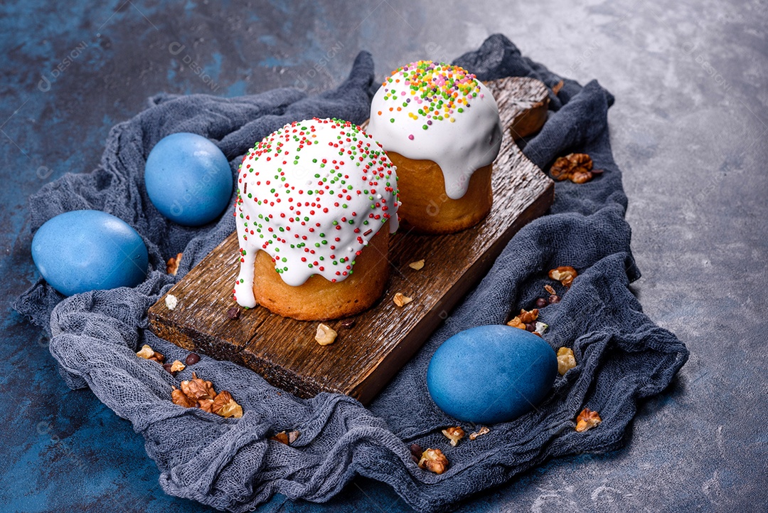 Bolos festivos com esmalte branco, nozes e passas com ovos de Páscoa na mesa festiva. Preparativos para a Páscoa