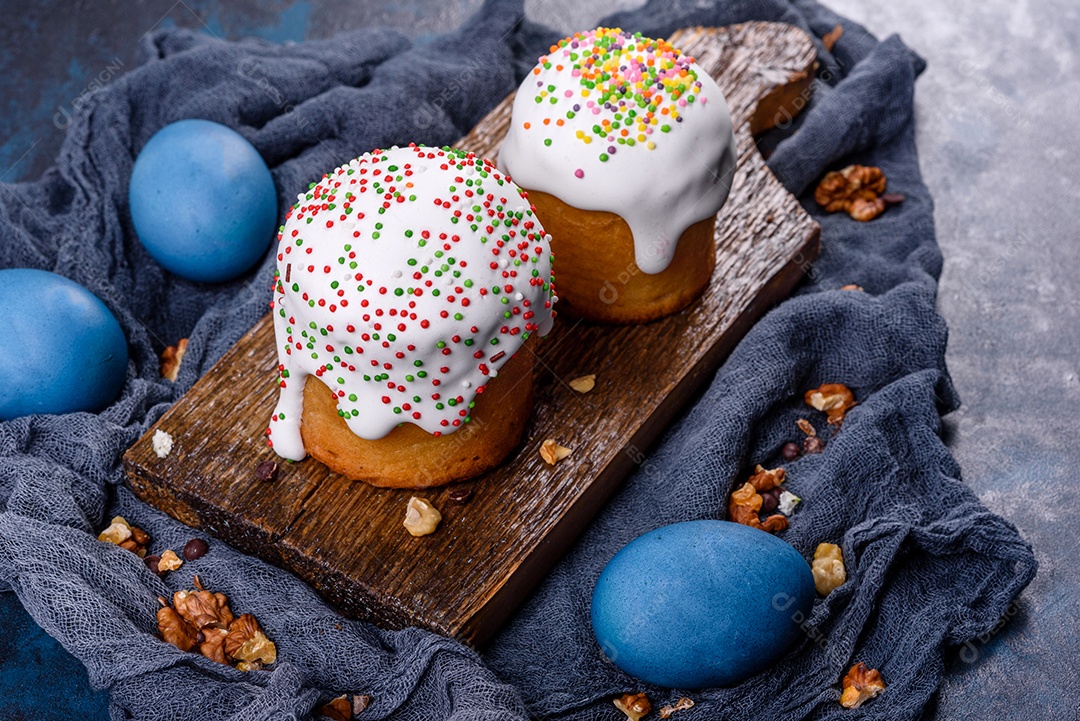 Bolos festivos com esmalte branco, nozes e passas com ovos de Páscoa na mesa festiva. Preparativos para a Páscoa