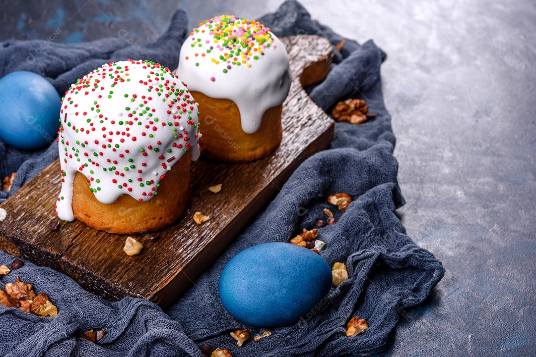 Bolos festivos com esmalte branco, nozes e passas com ovos de Páscoa na mesa festiva. Preparativos para a Páscoa
