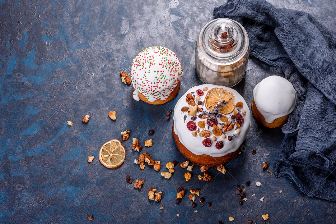 Bolos festivos com esmalte branco, nozes e passas com ovos de Páscoa na mesa festiva. Preparativos para a Páscoa