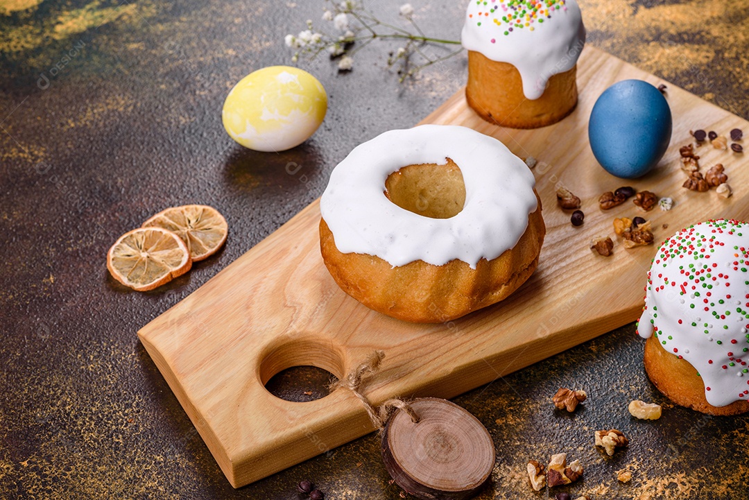 Bolos festivos com esmalte branco, nozes e passas com ovos de Páscoa na mesa festiva. Preparativos para a Páscoa