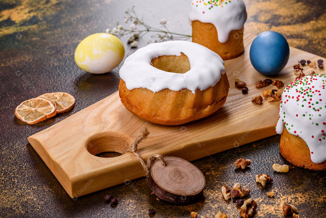 Bolos festivos com esmalte branco, nozes e passas com ovos de Páscoa na mesa festiva. Preparativos para a Páscoa