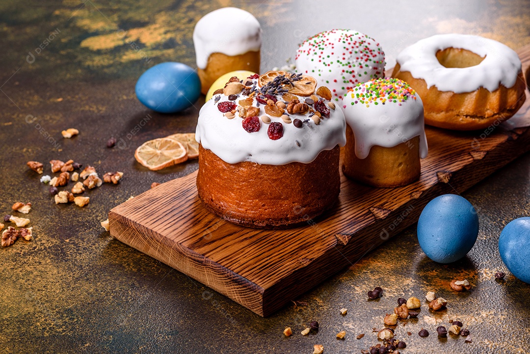 Bolos festivos com esmalte branco, nozes e passas com ovos de Páscoa na mesa festiva. Preparativos para a Páscoa