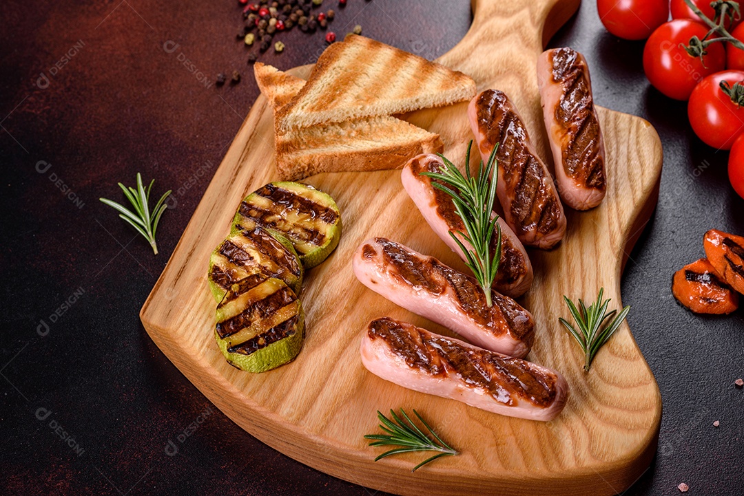 Saborosos enchidos frescos grelhados com legumes, especiarias e ervas. Foto do prato acabado em uma mesa de concreto escuro