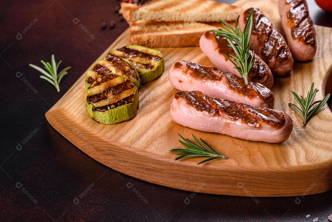 Saborosos enchidos frescos grelhados com legumes, especiarias e ervas. Foto do prato acabado em uma mesa de concreto escuro
