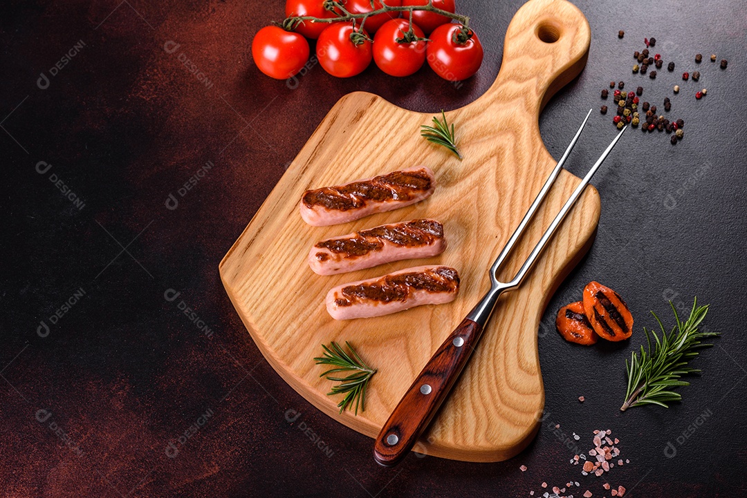 Saborosos enchidos frescos grelhados com legumes, especiarias e ervas. Foto do prato acabado em uma mesa de concreto escuro