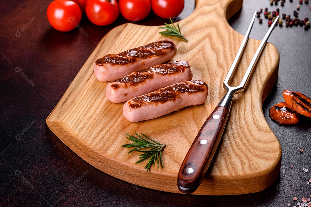 Saborosos enchidos frescos grelhados com legumes, especiarias e ervas. Foto do prato acabado em uma mesa de concreto escuro