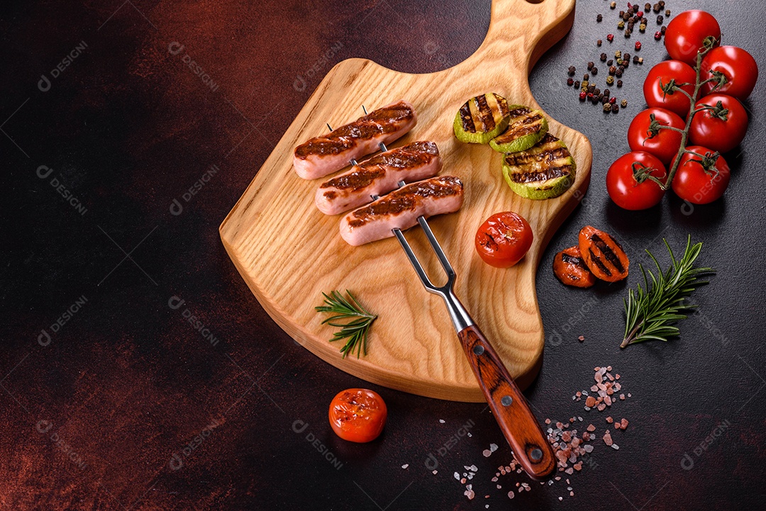 Saborosos enchidos frescos grelhados com legumes, especiarias e ervas. Foto do prato acabado em uma mesa de concreto escuro