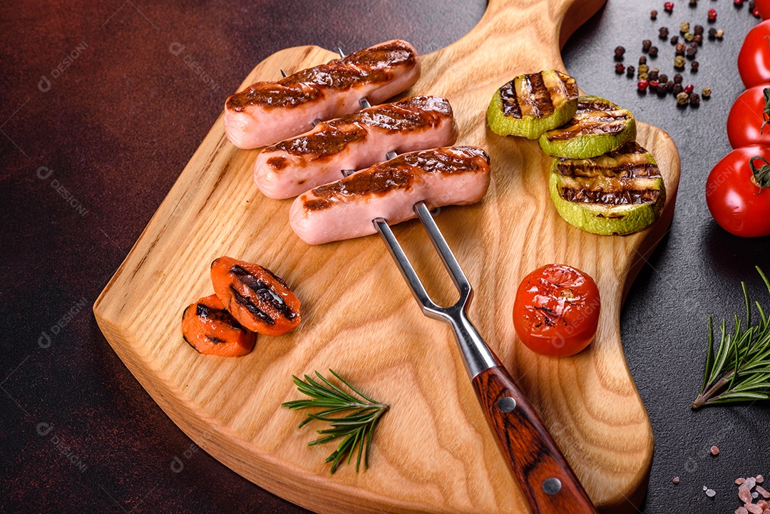 Saborosos enchidos frescos grelhados com legumes, especiarias e ervas. Foto do prato acabado em uma mesa de concreto escuro