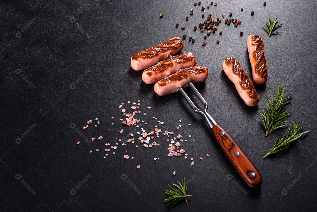 Saborosos enchidos frescos grelhados com legumes, especiarias e ervas. Foto do prato acabado em uma mesa de concreto escuro
