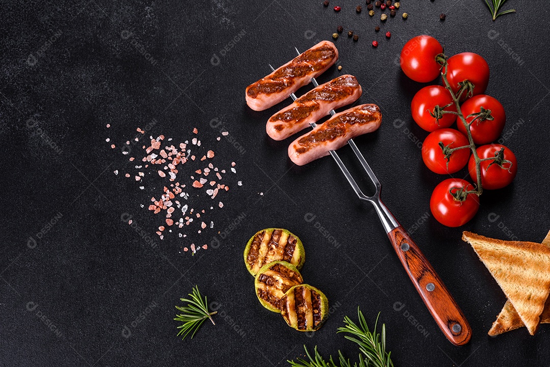 Saborosos enchidos frescos grelhados com legumes, especiarias e ervas. Foto do prato acabado em uma mesa de concreto escuro