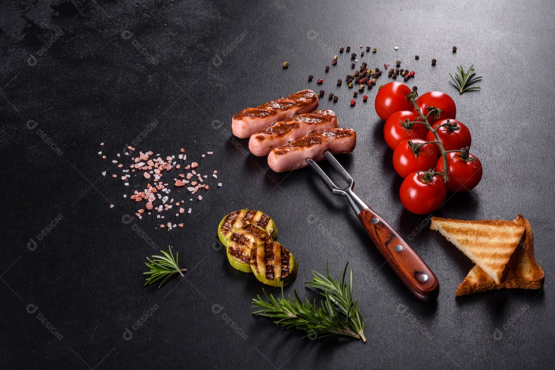 Saborosos enchidos frescos grelhados com legumes, especiarias e ervas. Foto do prato acabado em uma mesa de concreto escuro
