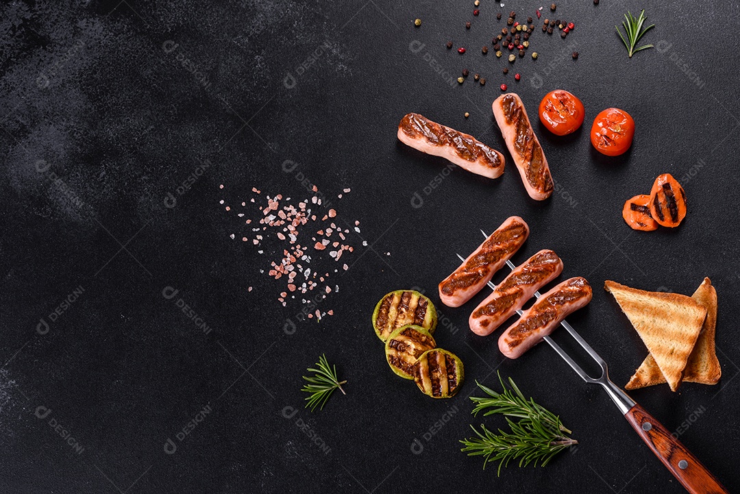 Saborosos enchidos frescos grelhados com legumes, especiarias e ervas. Foto do prato acabado em uma mesa de concreto escuro