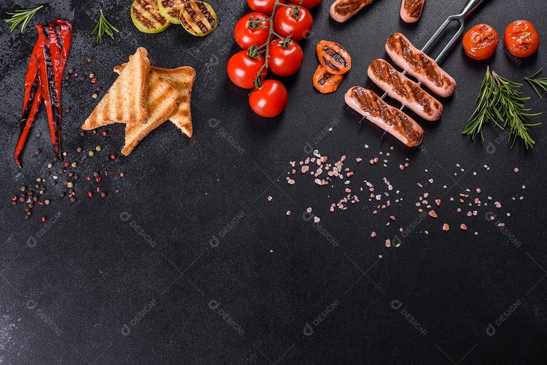 Saborosos enchidos frescos grelhados com legumes, especiarias e ervas. Foto do prato acabado em uma mesa de concreto escuro