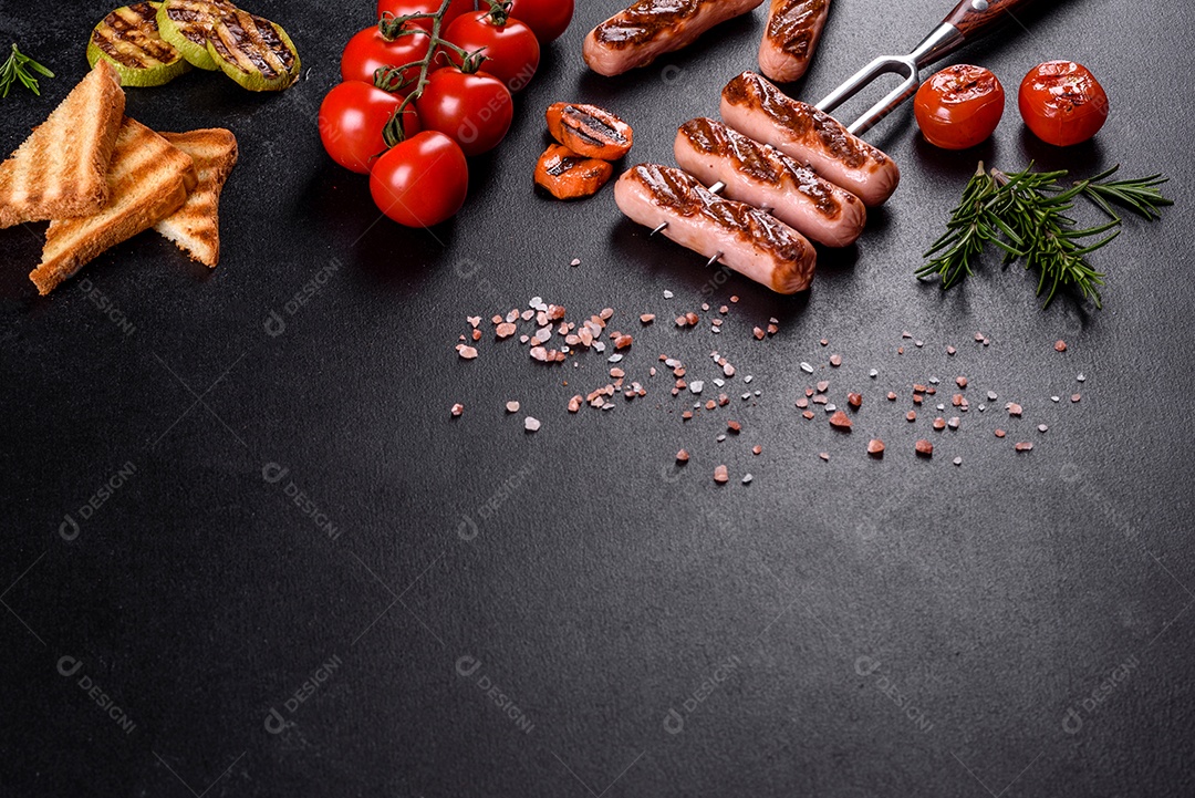 Saborosos enchidos frescos grelhados com legumes, especiarias e ervas. Foto do prato acabado em uma mesa de concreto escuro