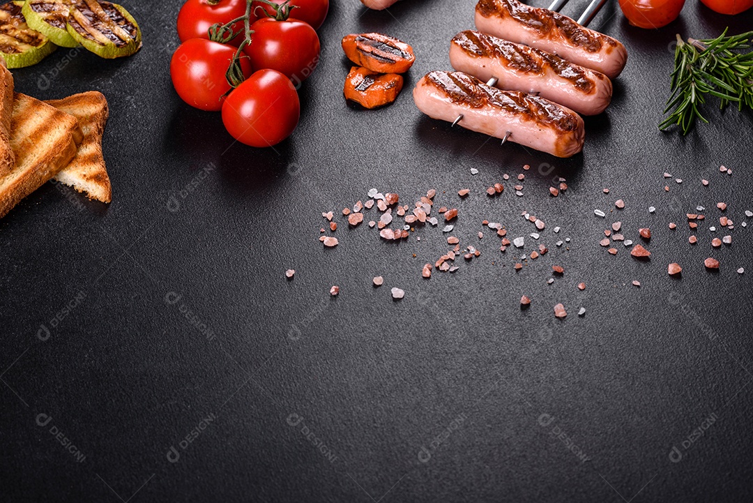 Saborosos enchidos frescos grelhados com legumes, especiarias e ervas. Foto do prato acabado em uma mesa de concreto escuro