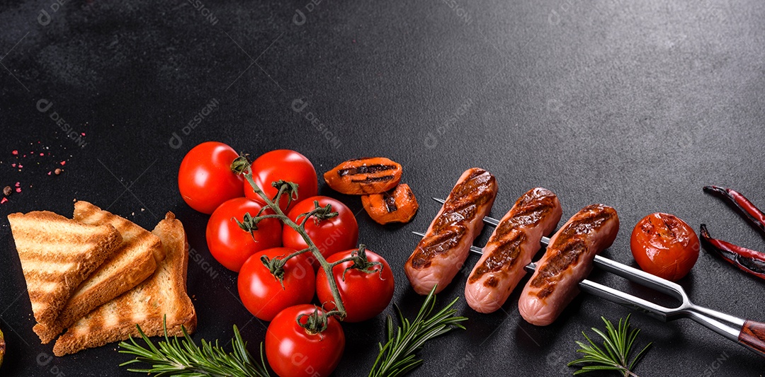 Saborosos enchidos frescos grelhados com legumes, especiarias e ervas. Foto do prato acabado em uma mesa de concreto escuro