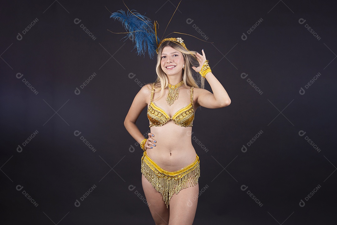 Linda passista loira fantasiada para o carnaval sobre um fundo isolado preto.