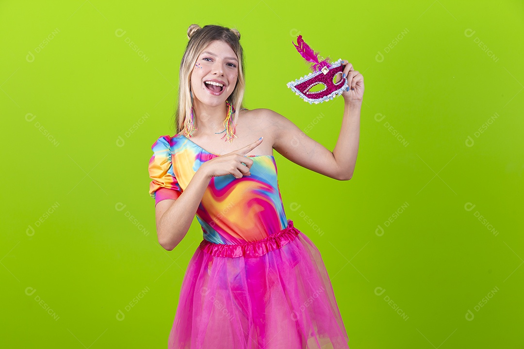 Linda mulher loira segurando máscara carnavalesca sobre um fundo isolado verde.