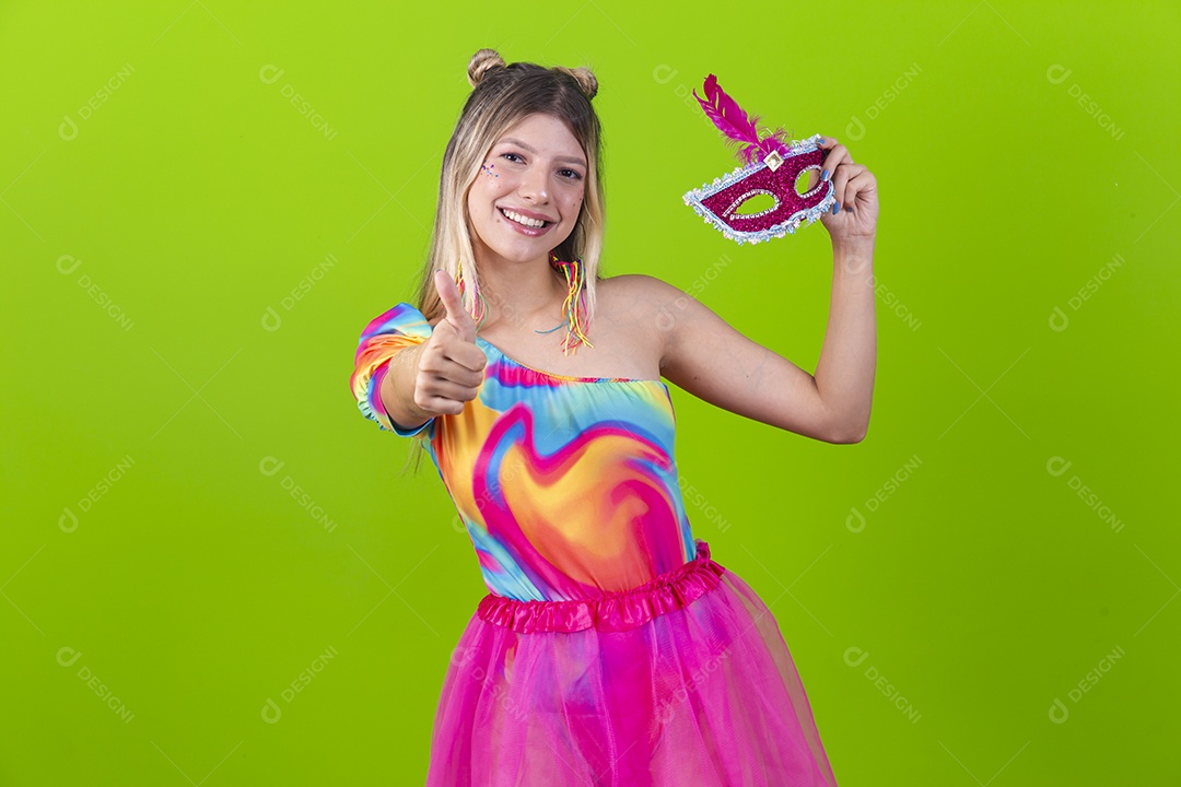 Linda mulher loira segurando máscara carnavalesca sobre um fundo isolado verde.