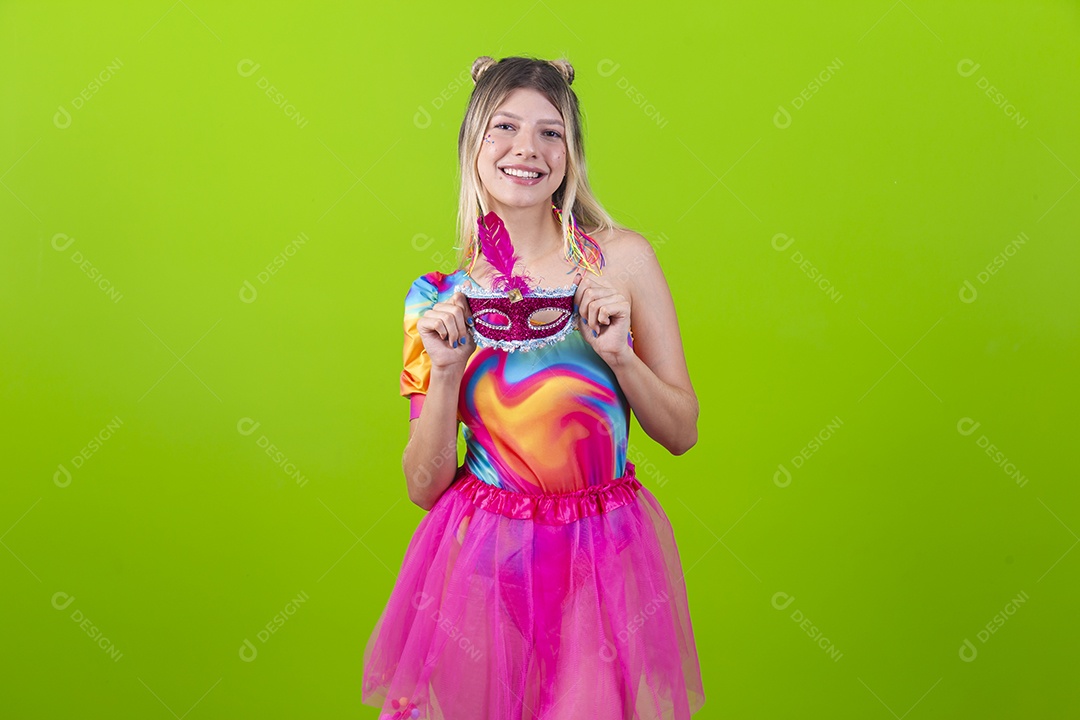 Linda mulher loira segurando máscara carnavalesca sobre um fundo isolado verde.