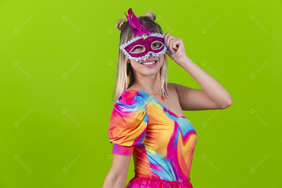 Linda mulher loira usando máscara carnavalesca sobre um fundo isolado verde.