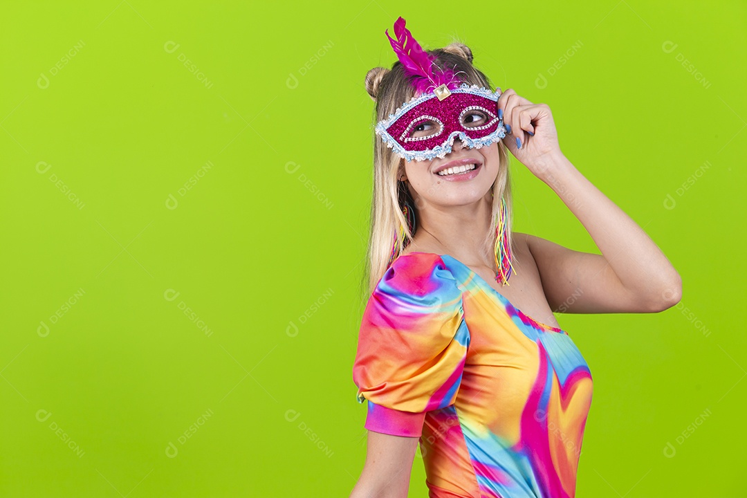Linda mulher loira usando máscara carnavalesca sobre um fundo isolado verde.