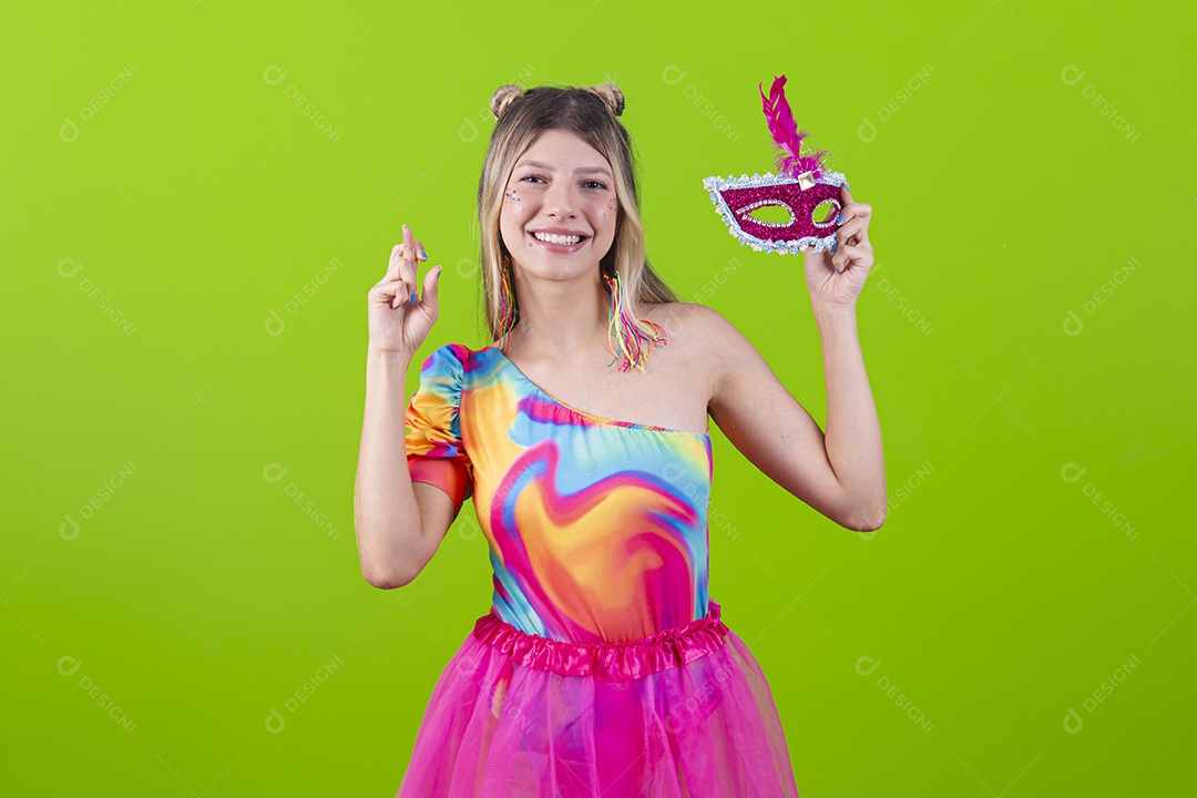 Linda mulher loira segurando máscara carnavalesca sobre um fundo isolado verde.