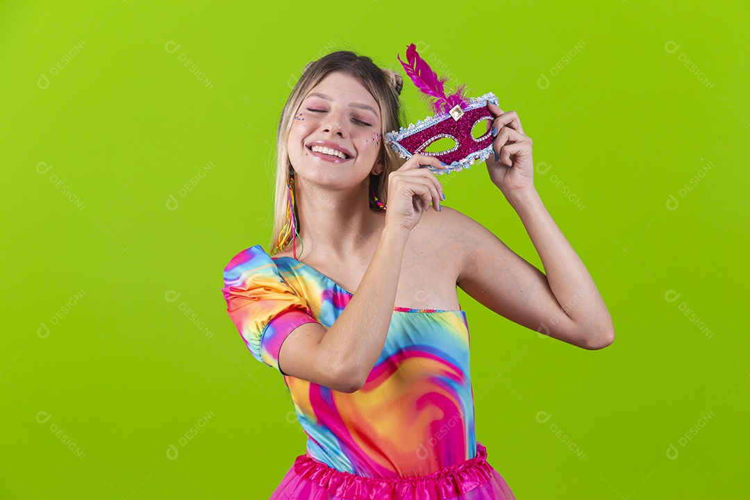 Linda mulher loira usando máscara carnavalesca sobre um fundo isolado verde.