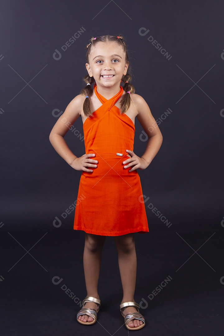 Linda menina vestida com vestido laranja sobre um fundo isolado preto,