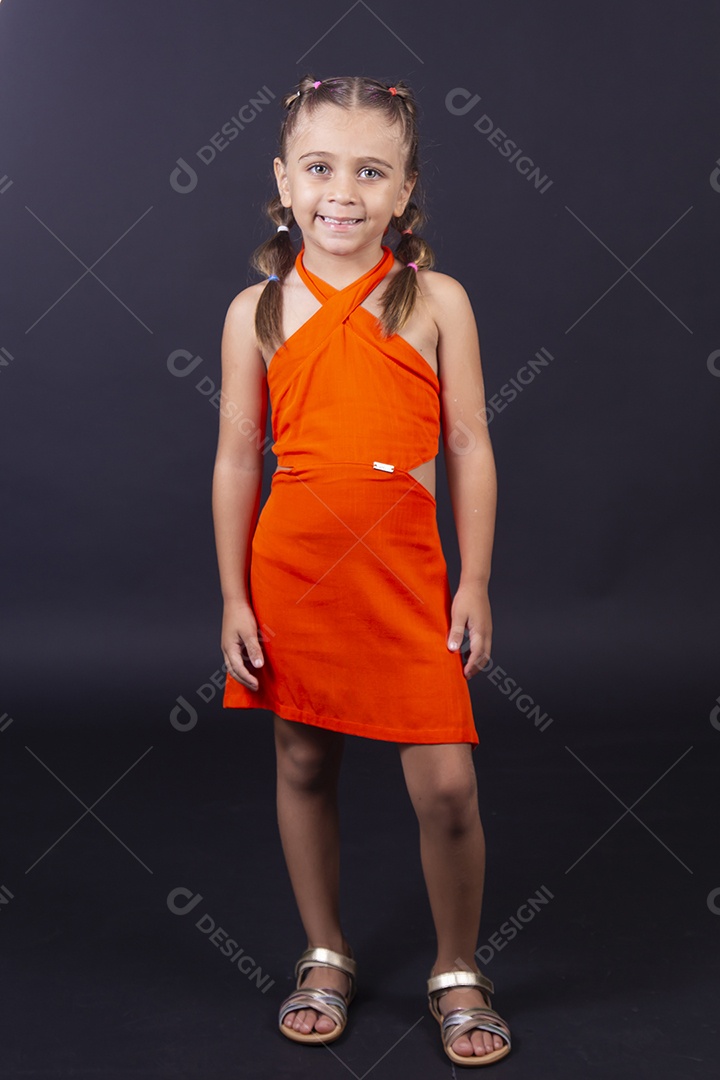 Linda menina vestida com vestido laranja sobre um fundo isolado preto