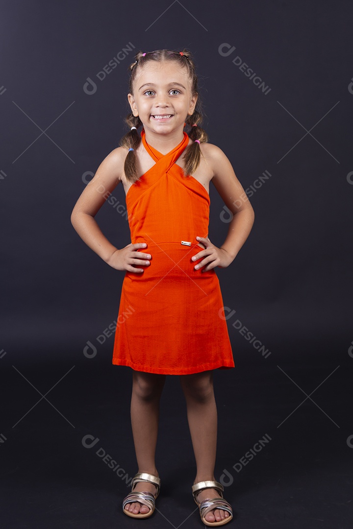 Linda menina vestida com vestido laranja sobre um fundo isolado preto
