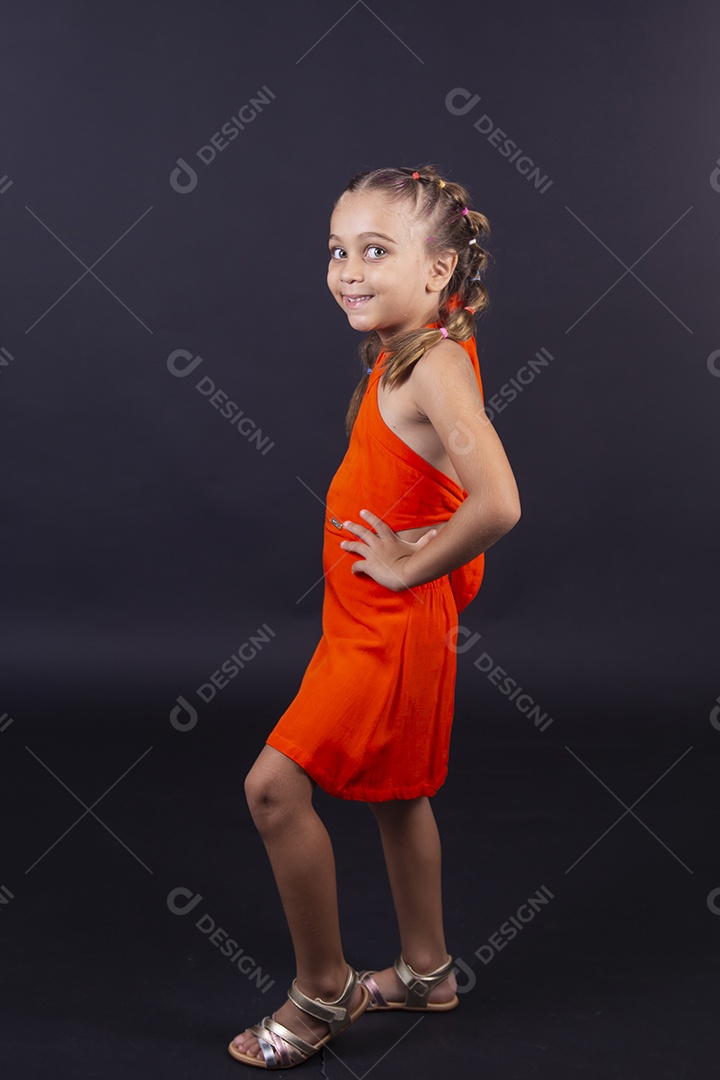 Linda menina vestida com vestido laranja sobre um fundo isolado preto