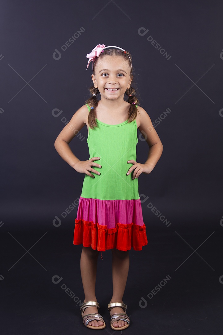Linda menina usando vestido colorido sobre um fundo isolado preto.