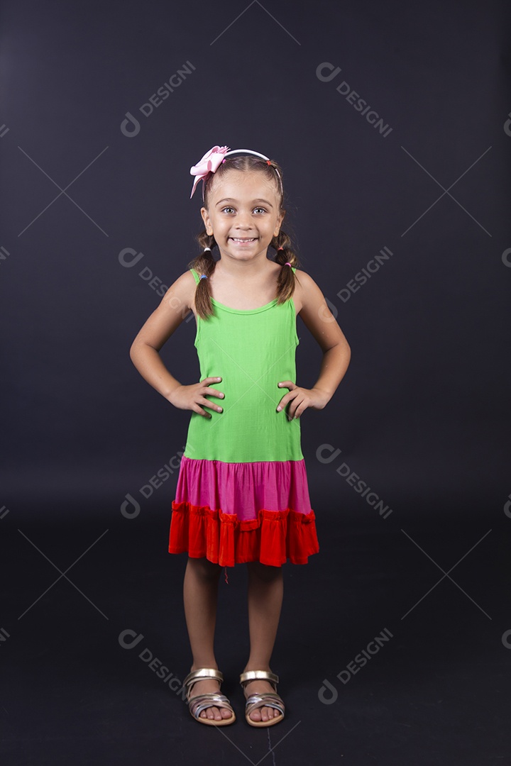 Linda menina usando vestido colorido sobre um fundo isolado preto.