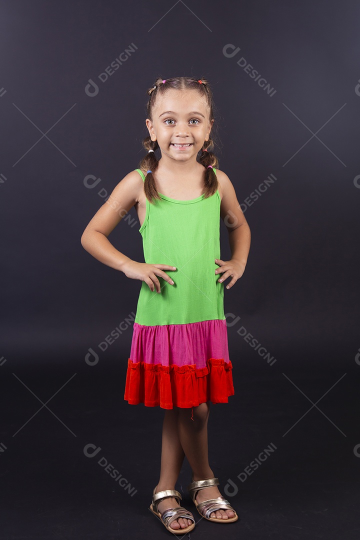 Linda menina usando vestido colorido sobre um fundo isolado preto.