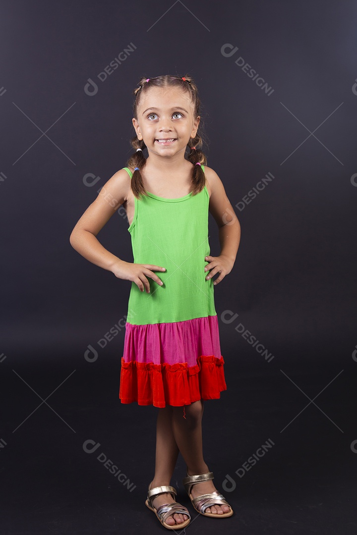 Linda menina usando vestido colorido sobre um fundo isolado preto.