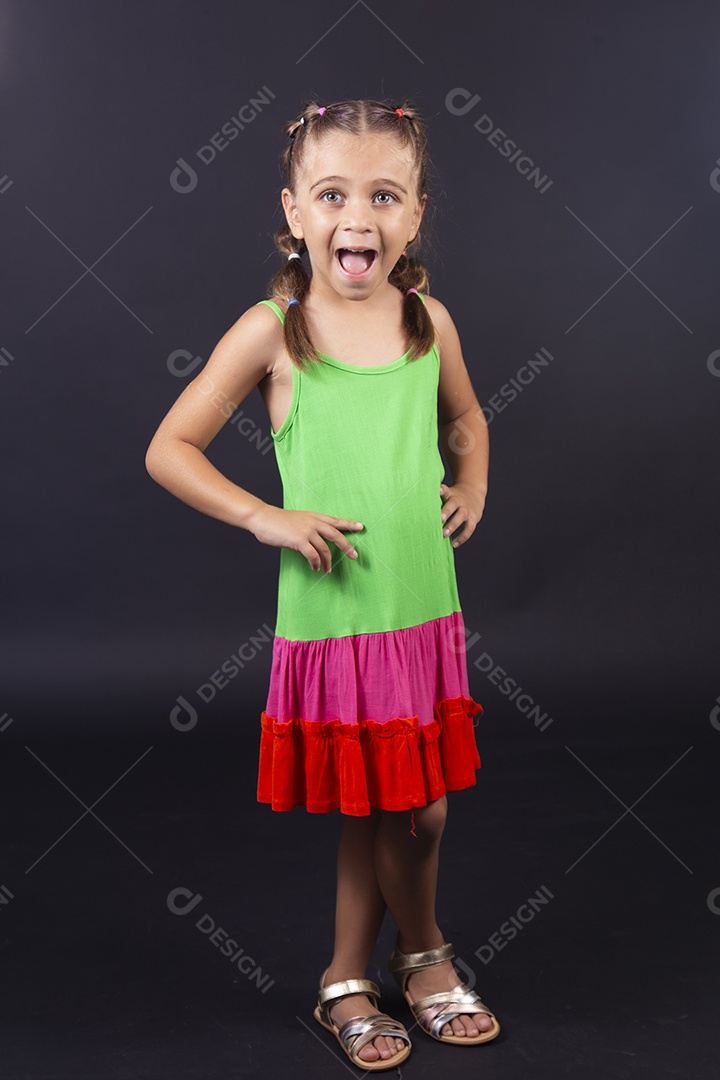 Linda menina usando vestido colorido sobre um fundo isolado preto.