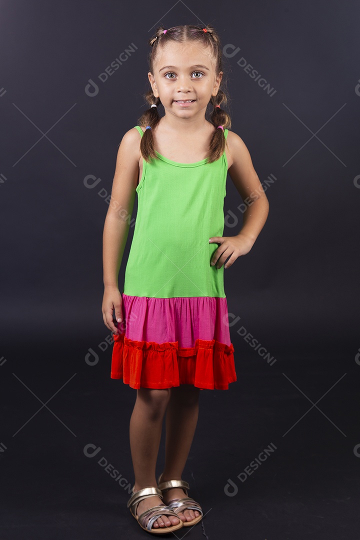 Linda menina usando vestido colorido sobre um fundo isolado preto.