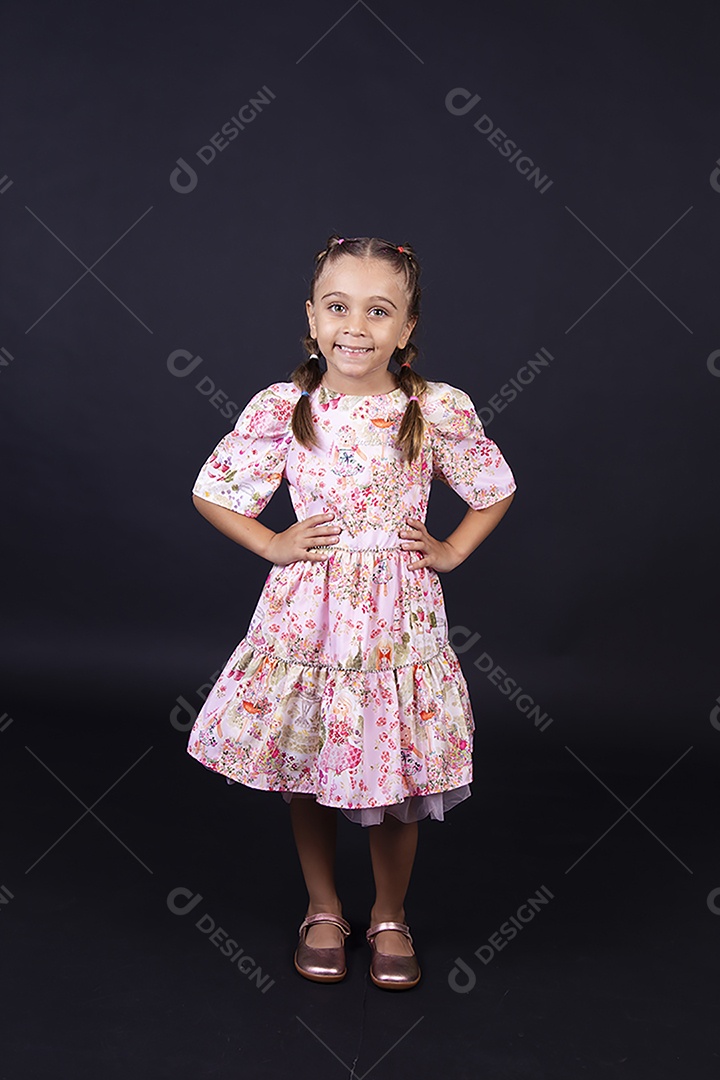 Linda menina usando vestido florido sobre um fundo isolado preto.