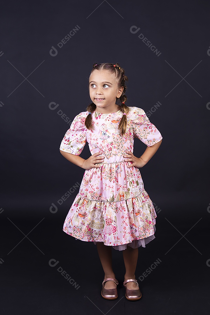 Linda menina usando vestido florido sobre um fundo isolado preto.