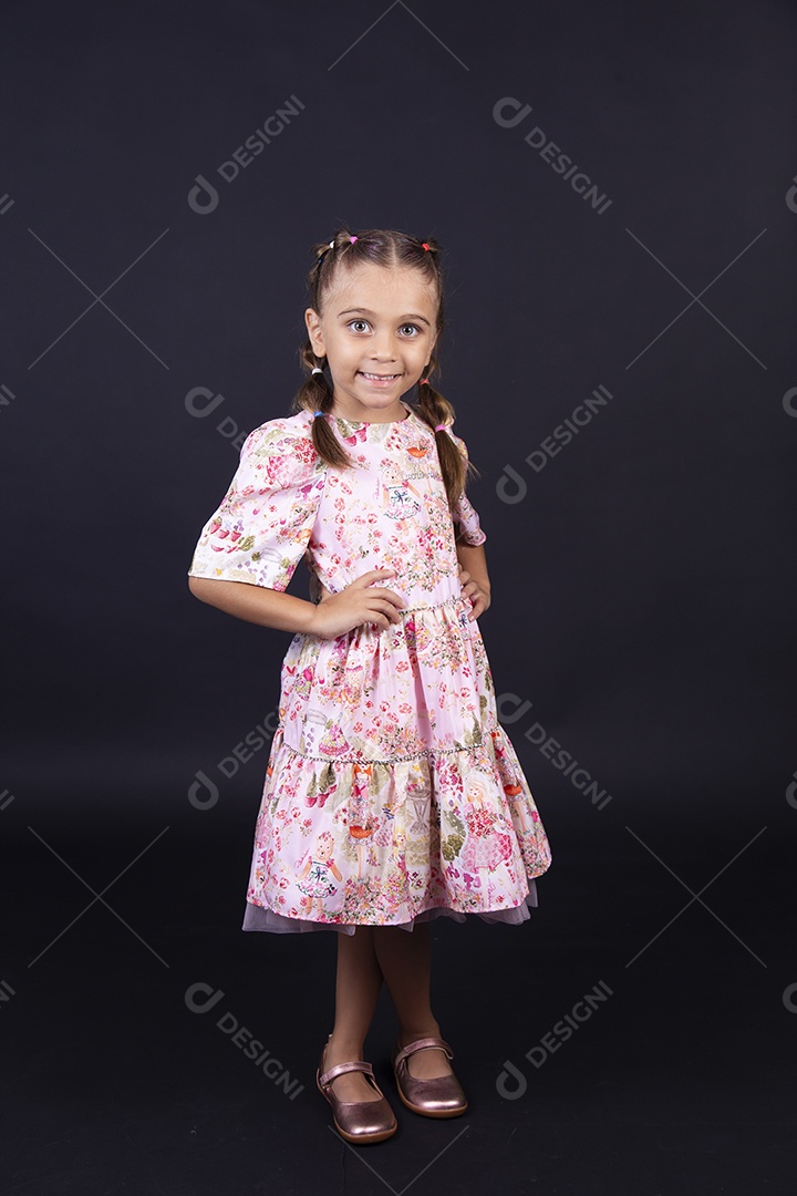 Linda menina usando vestido colorido sobre um fundo isolado preto.